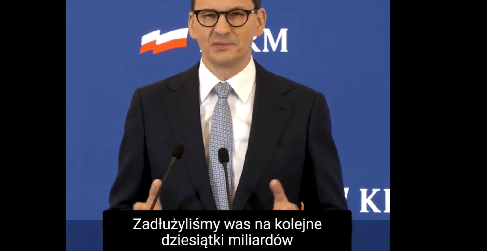 Morawiecki na konferencji o tarczy antyinflacyjnej i napisy "Zadłużyliśmy was na kolejne dziesiątki miliardów
